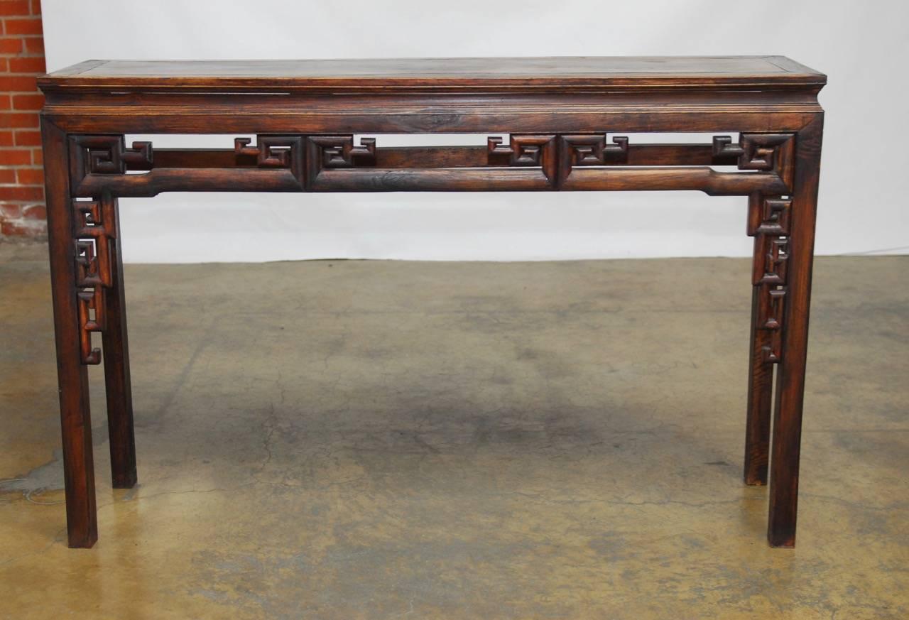 Handsome Qing dynasty carved altar table or scroll table with a floating top panel. Features an intricate Greek key decoration on the front and humpback stretchers on the sides. Supported by long square legs.