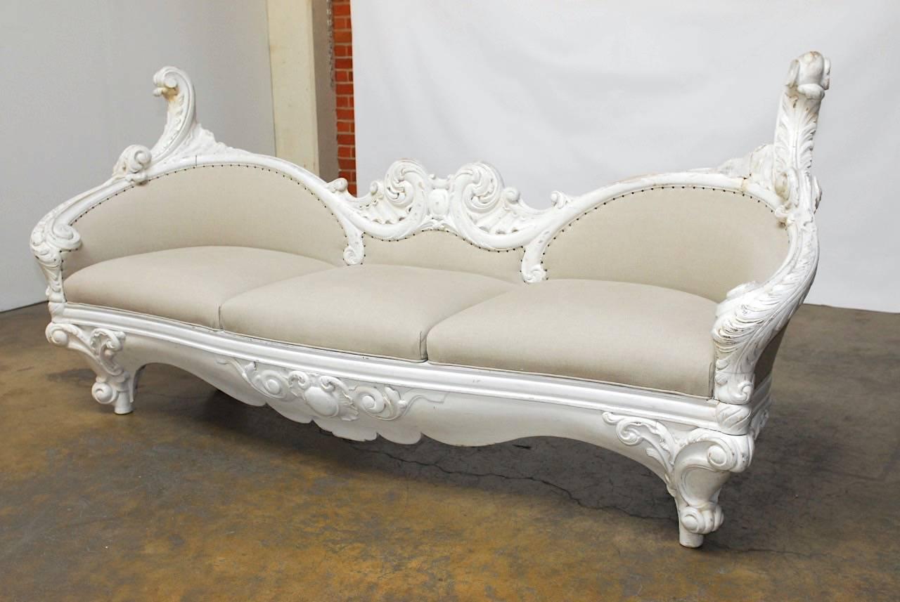 Magnificent French Rococo or late Baroque painted sofa decorated with a whimsical Rocaille carved frame. Encased in scroll designs reminiscent of Versailles grottos. Newly refurbished in an organic Irish linen fabric seat bordered with exposed