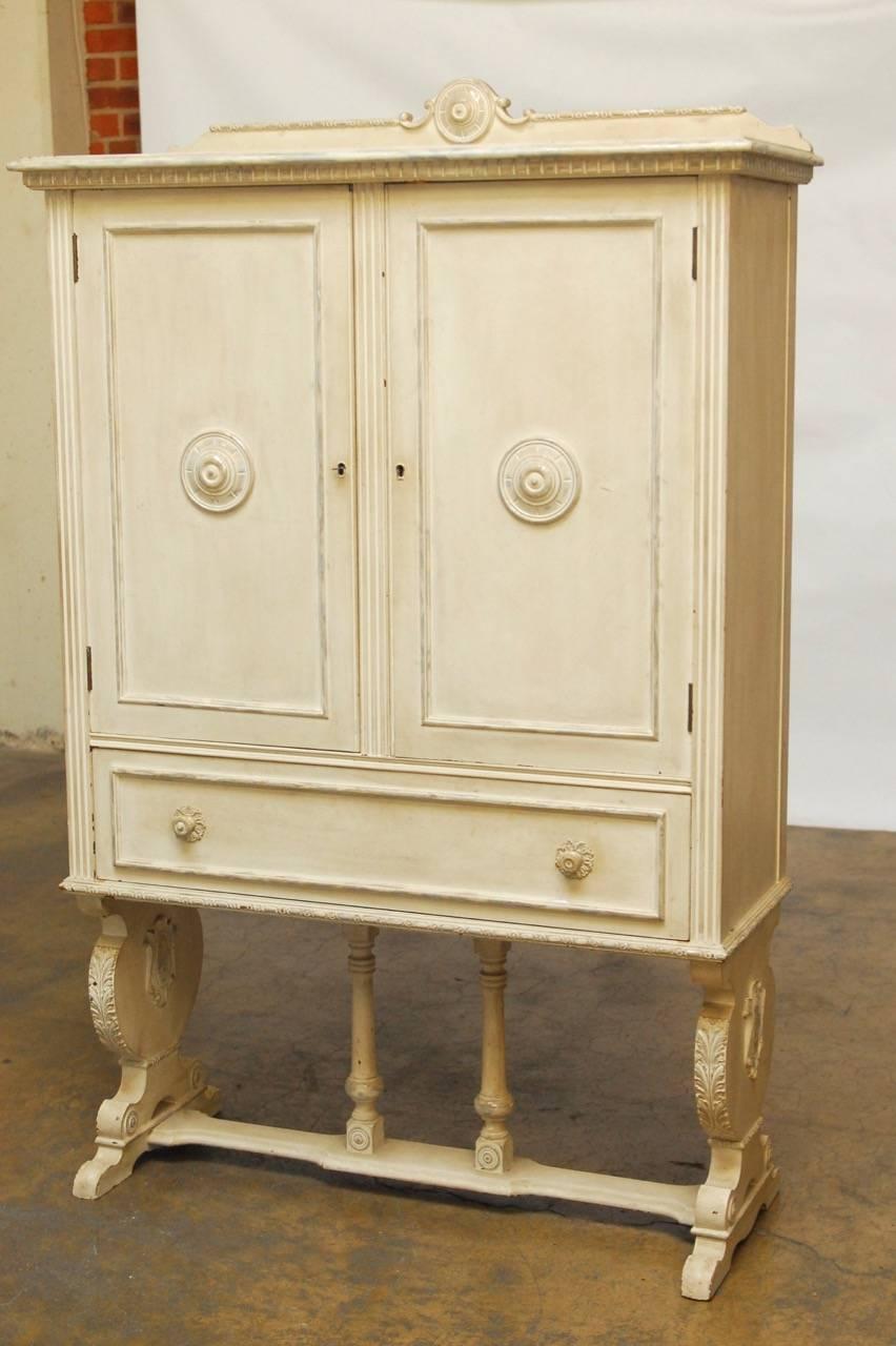 Exquisite Swedish buffet cupboard or china cabinet featuring a painted and distressed white finish. Rare cabinet fronted by two large locking doors with three plate storage shelves inside and a large storage drawer below. Beautifully detailed with