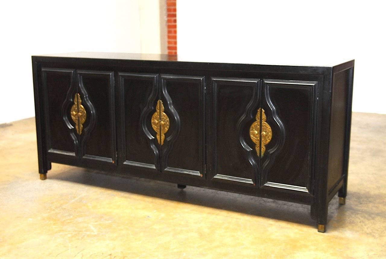 Stunning black lacquer sideboard buffet dresser designed by Century furniture in the style of James Mont. Features Asian influenced brass door pulls with conforming paneled trim. Fronted by three sets of doors that open to storage areas. Supported