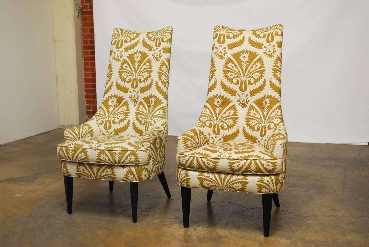 Fabulous pair of Mid-Century style high back accent chairs by Jonathan Adler. Iconic style with a seat cushion and an elongated three button back. Supported by splayed legs in the rear and tapered front legs. Upholstered in a printed fabric called