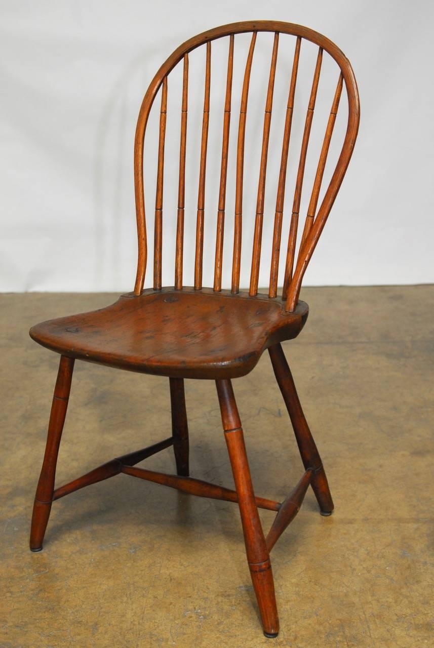 Assembled pair of rustic bow back Windsor chairs featuring a nine spindle back. One chair is supported by a turned leg while the other has a smooth bamboo style. Both have 