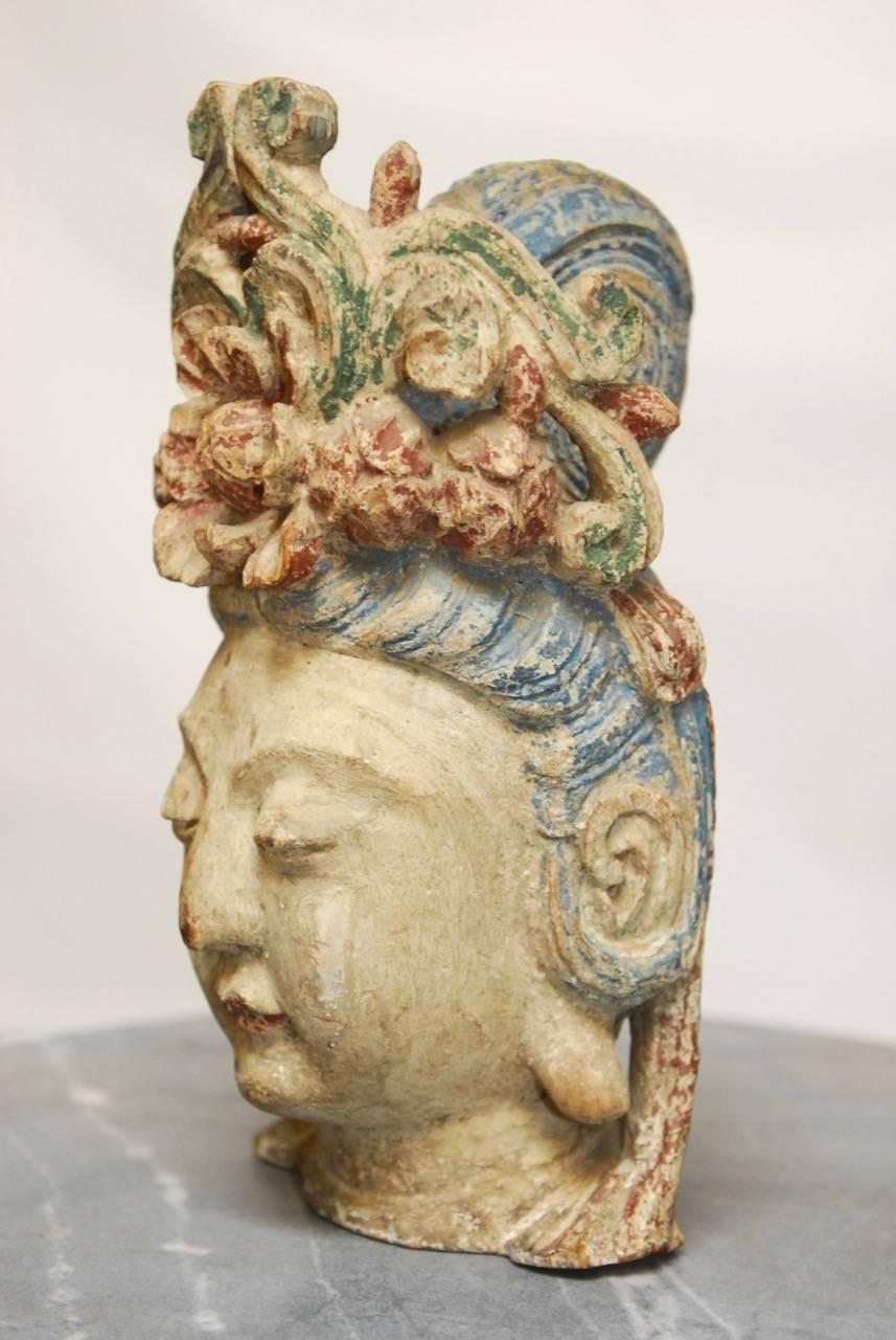 Mesmerizing carved Guan Yin Bodhisattva wooden head featuring a faded polychrome decorated floral diadem and high chignon. The statue is beautifully carved with Fine features and a rich patina.