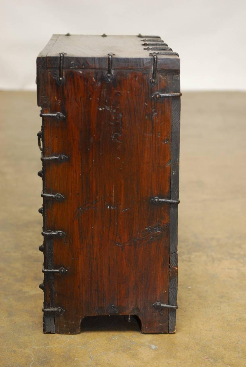 Distinctive Korean Tansu Bandaji style chest or blanket chest made of elm. Featuring iron hardware, lock plates and strapping. Small Campaign scale fronted by three drawers on top and two hinged doors that open to inside storage. Inside is decorated