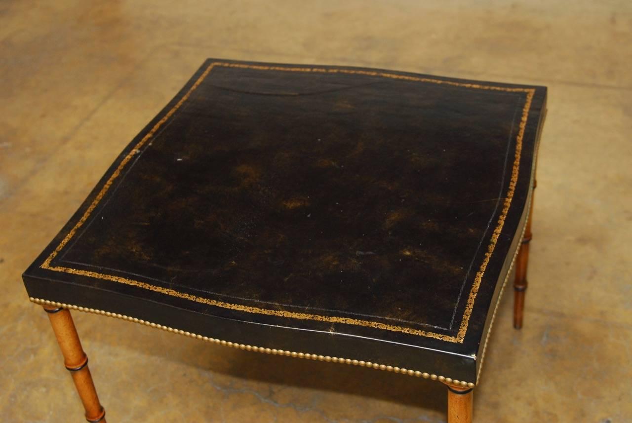 Exquisite mahogany games table featuring a tooled black leather surface and supported by faux bamboo legs. Made in the Regency taste with a decorative gilt border and brass nailhead trim on the apron. Maker's mark on bottom Barnard and Simonds Co.