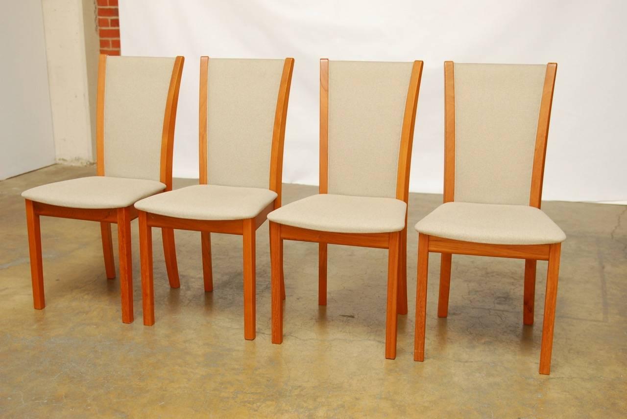 Elegant set of Danish dining chairs by Skovby made of teak featuring rich grain patterns and a neutral colored fabric with a subtle textured pattern. Supported by square legs and a graceful arched back. Makers label affixed to bottom. Excellent