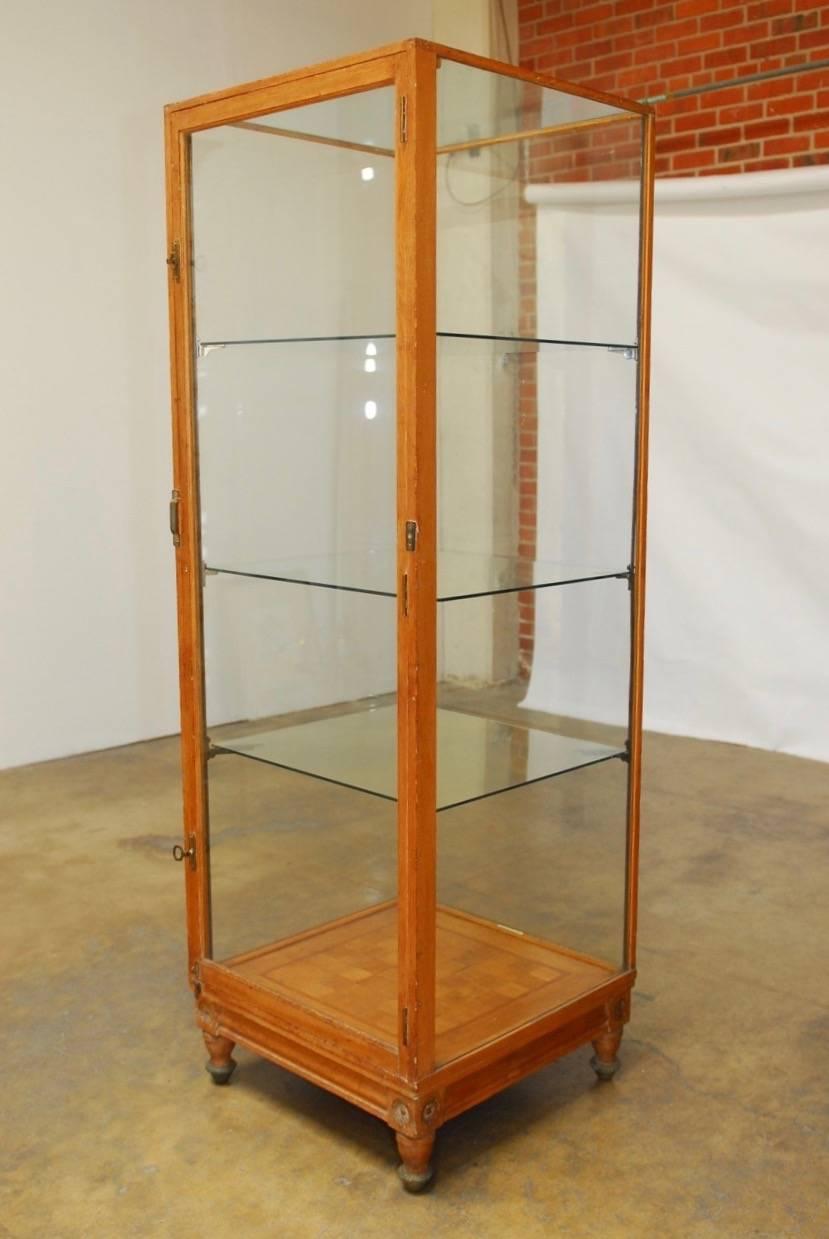 Fantastic 19th century English oak haberdashery display cabinet or vitrine produced by Frederick Sage and Company. Features a four shelf display with adjustable shelves and a parquet floor. The door has two locking handles and bottom loop for a pad