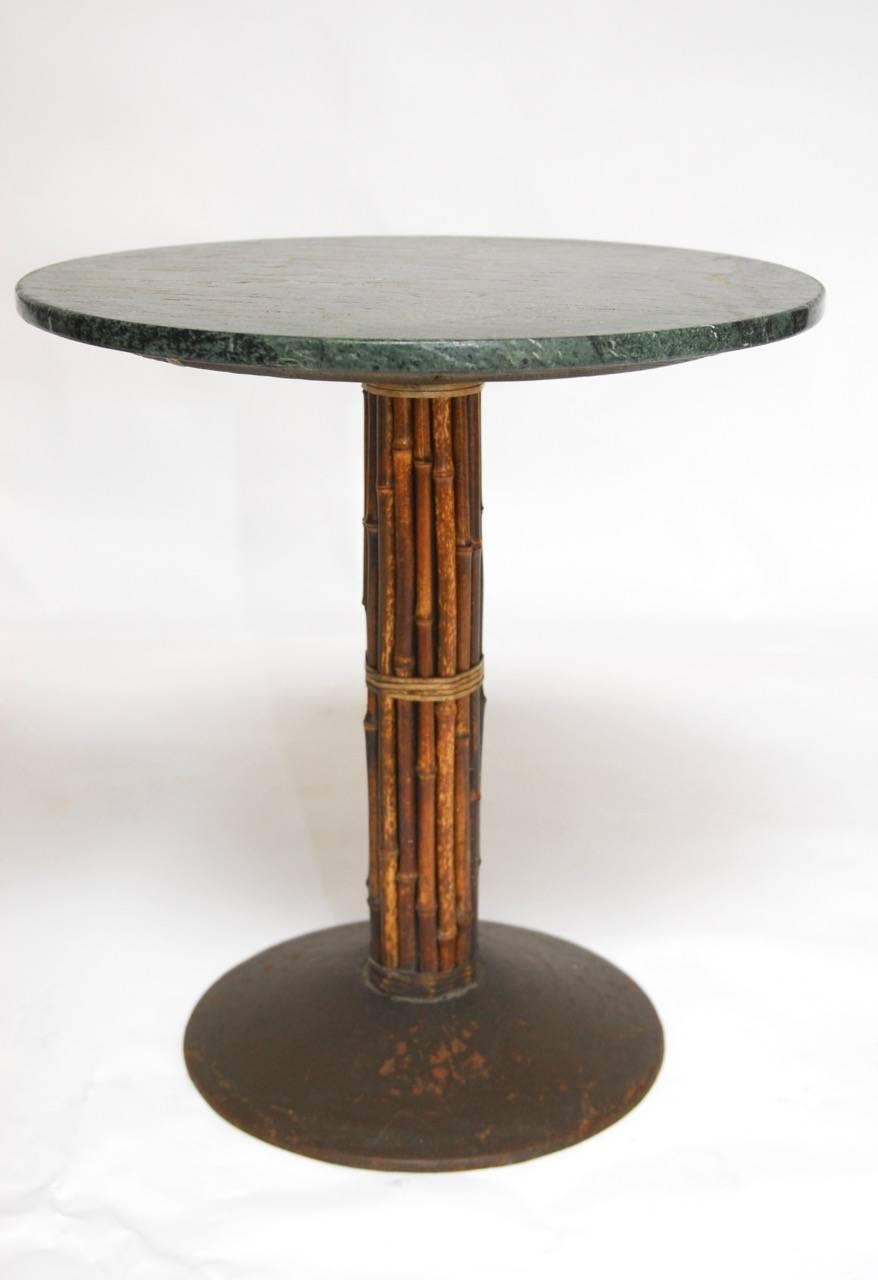 Fabulous set of four marble top Bistro style tables featuring a bamboo and rawhide covered metal pedestal by McGuire. The tops have a deeply veined green and white marble with a soft worn finish. Provenance: From the historic "Lion's Pub",