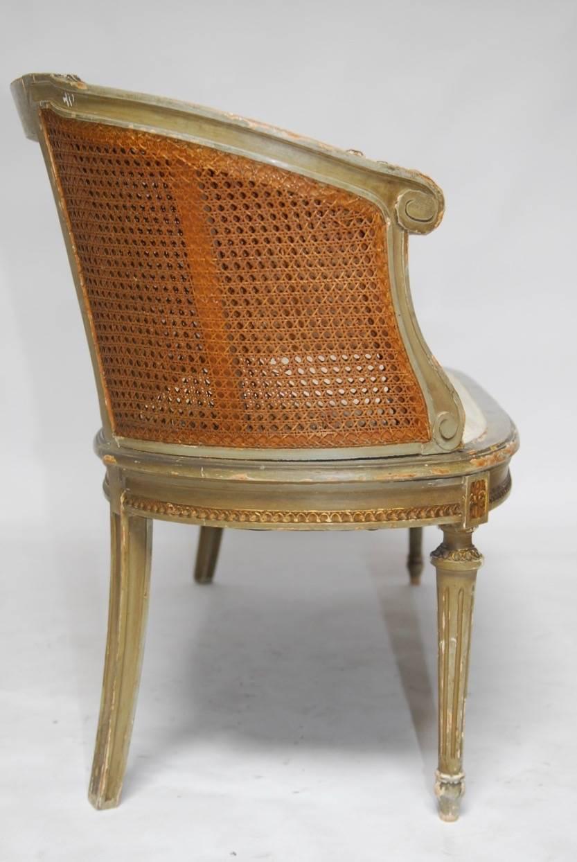 Elegant French Louis XVI cane settee or canape en corbeille. Featuring an intricately carved frame in a basket form with an hourglass window of floral swag design and double caned sides. Originally finished in a 