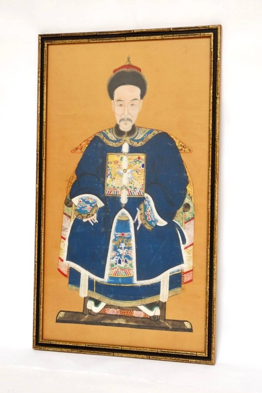 Colorful Chinese Qing dynasty ancestor portrait of a high ranking official or ruler depicted sitting with a beautifully embroidered robe decorated with rank badges. Bright colors are accented by gold leaf and mounted into a giltwood frame.