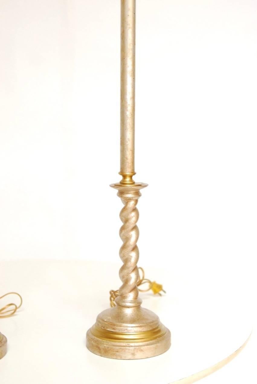 Attractive pair of silver gilt candlestick table lamps featuring a barley twist form and brass hardware, rings, and finials. Produced by Kinder-Harris from gilded metal in a silver finish with brass accents. Includes harps and finials but no shades.