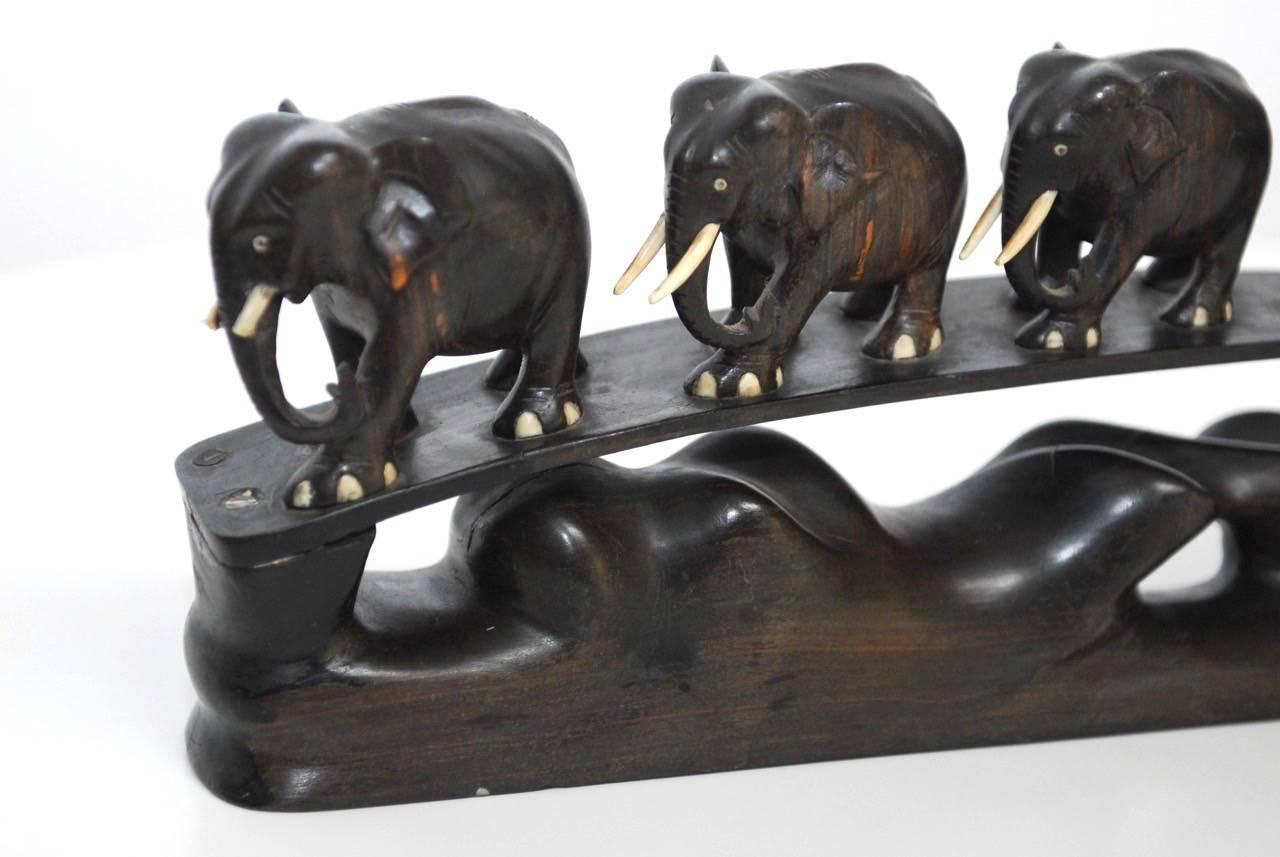 Delightful Anglo-Indian carving depicting six elephants crossing over a bridge of water. Graduated sizes and each having white tusks. The ebonized wood has beautiful movement on the water and shows the skilled work of the craftsmen.