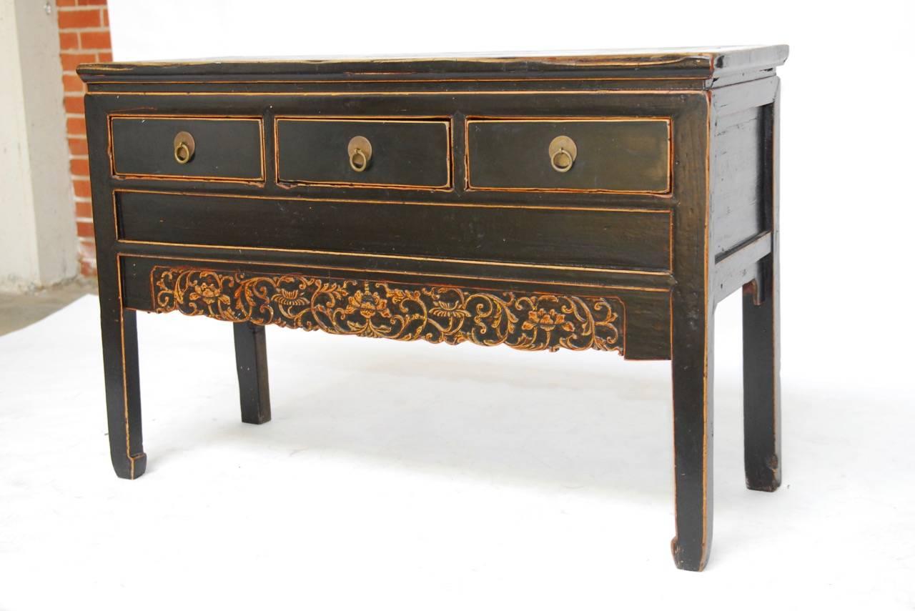 Exceptional Chinese black lacquered sideboard or console table fronted by three drawers and featuring a relief carved apron of scrolling vines. The altar style was constructed from 18th and 19th century wood and is supported by straight legs with