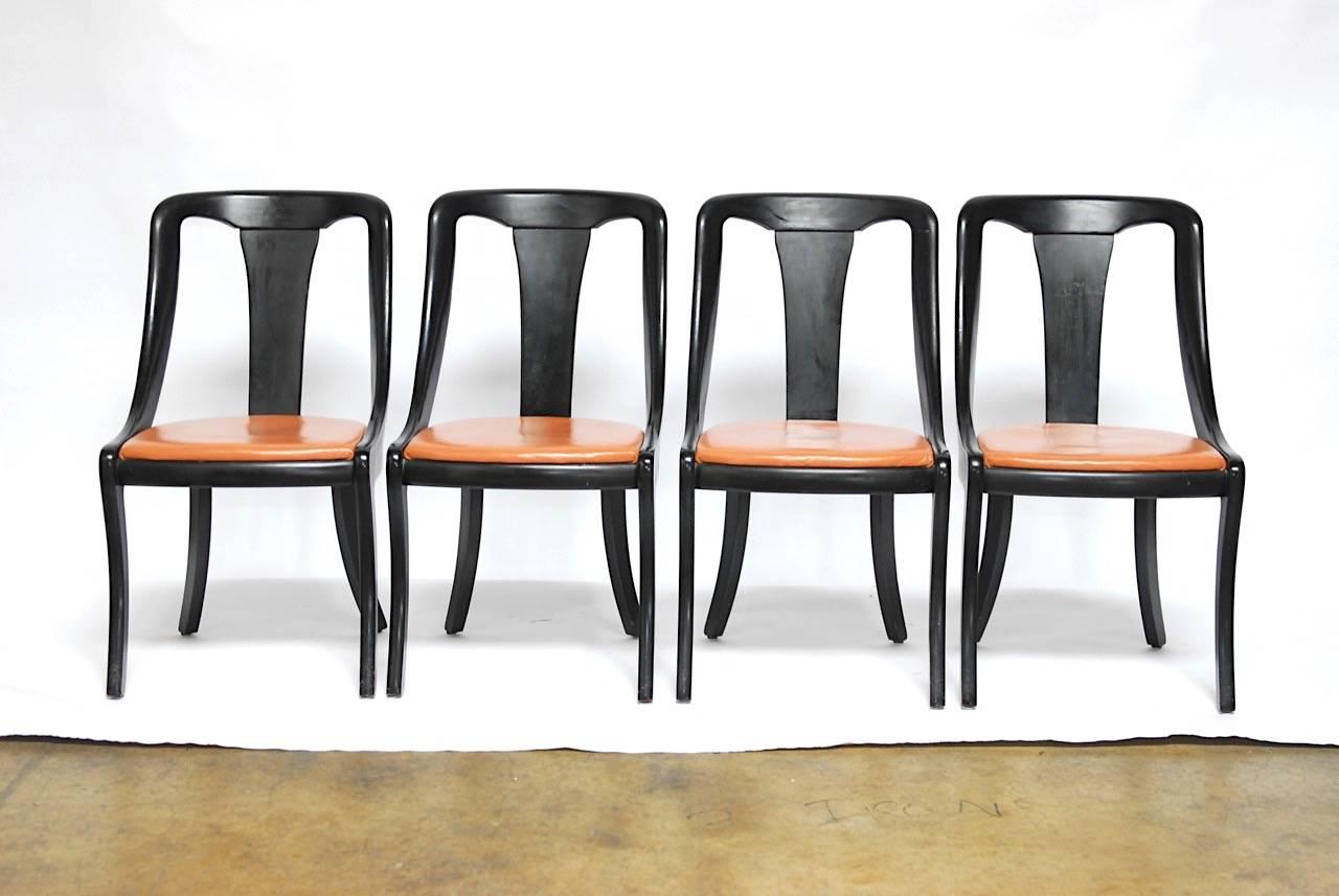 Stylish set of four Mid-Century dining chairs by Hickory Chair Co. featuring a klismos style saber leg and curved scoop back form with a black lacquer finish. Original vinyl upholstery with solid construction and a sleek Mid-Century design.