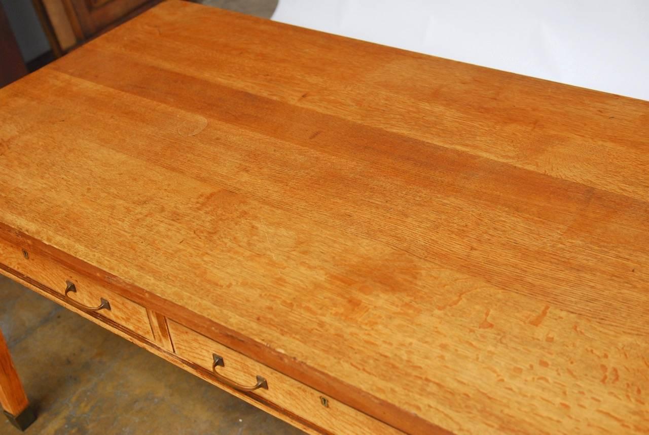 Generous solid oak library table or desk constructed from quartersawn oak and made in the Stickley Arts and Crafts style. This unsigned piece is fronted by two large drawers with brass pulls and hardware. The base is supported by gently tapered legs