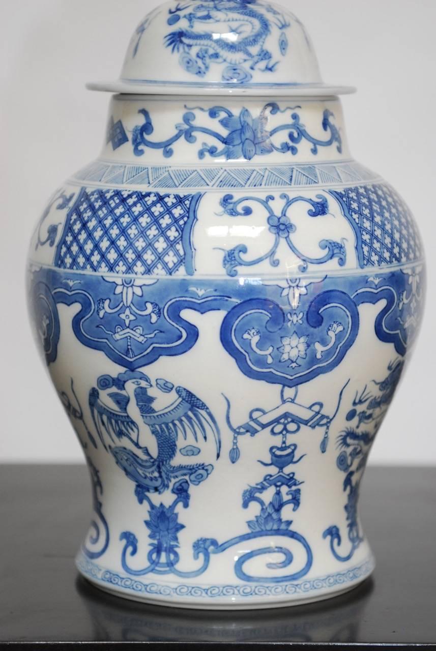 Beautiful Chinese blue and white porcelain ginger jar hand-painted with dragons and phoenix motif bordered by Ruyi cloud designs and quatrefoil patterns. This ginger jar appears to have a continental influence and style. Topped with a foo lion