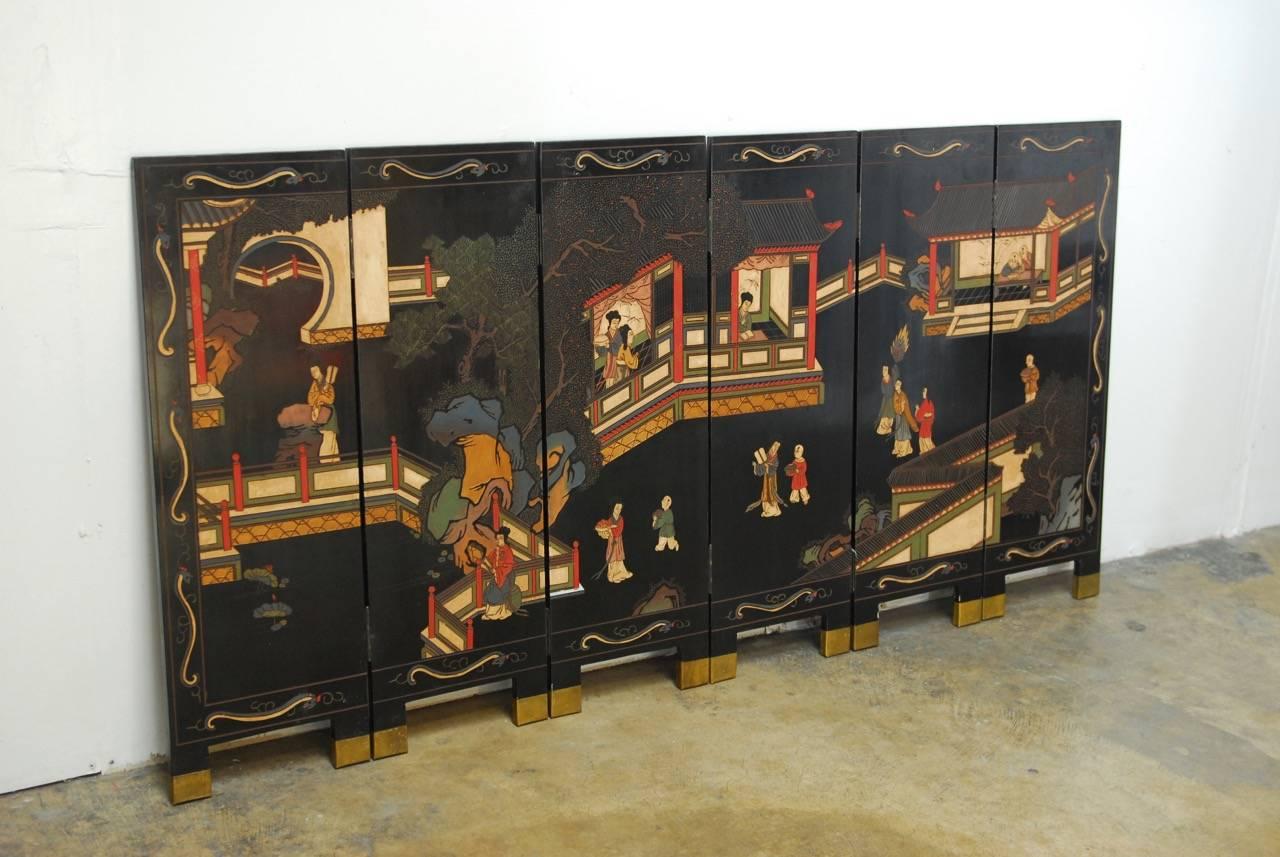 Mid-Century Chinese black lacquered six-panel coromandel folding table screen featuring thick layers of lacquer incised with a colorful court scene amid pagodas. The opposite side is decorated with a flower and bird motif. Heavy and solid supported