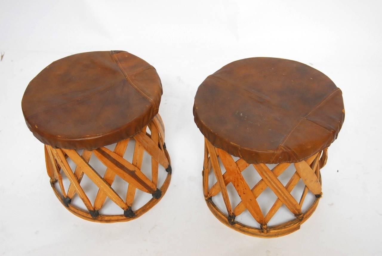 Rustic pair of mexican equipale style round drink tables with leather tops. Originally used as stools fashioned from Primitive slats of wood to form the body and a bentwood support on top and bottom.