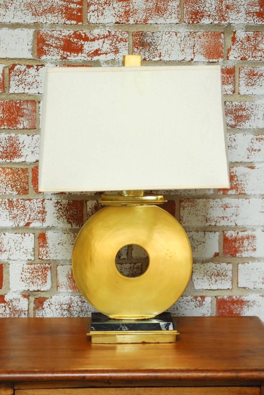 Fabulous pair of modern brass and marble table lamps designed by Robert Abbey. Constructed from solid brass and mounted to a sleek black marble base. Formed in the shape of a large "O" with a narrow profile. The lamps are accented by a