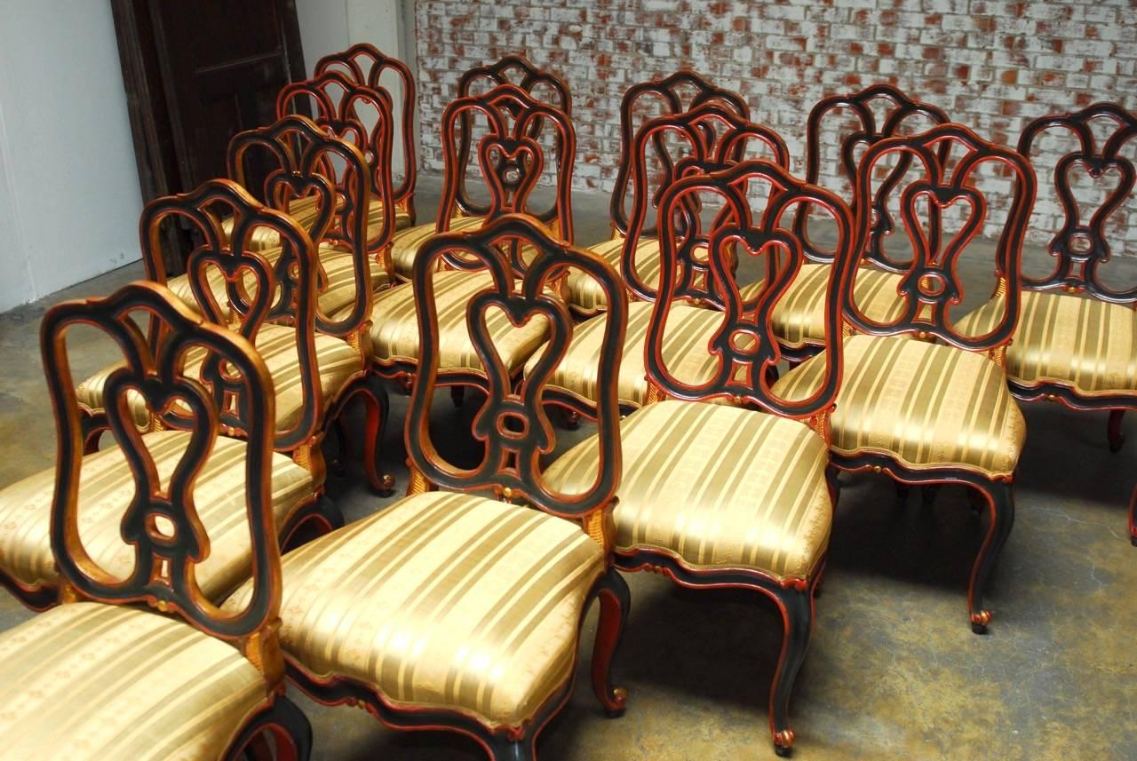 Fabulous set of 14 custom-made dining chairs by C. Mariani San Francisco CA. Made in the Italian Rococo taste with grand, generous proportions. Featuring a Classic hand-carved frame with a red and black lacquer finish accented by gilt trim. Each