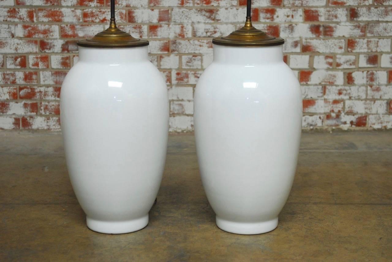 Monumental pair of Chinese blanc de chine baluster form vase table lamps. Large statement pieces with pleated shades and an adjustable height three head light. Vases measure 13 inches wide by 24 inches tall without brass hardware. Rewired using