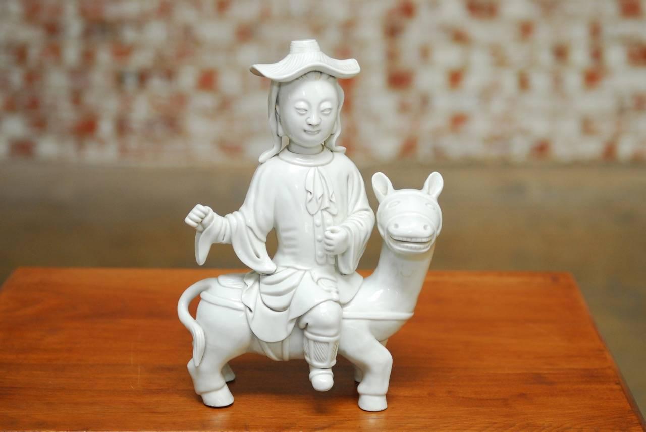 Whimsical Chinese Dehua Blanc de Chine porcelain man on horse. Featuring an Asian man wearing a European style robe depicted on horseback with his hands up. The porcelain has a milk white quality characteristic of Dehua porcelain. Stamped on back