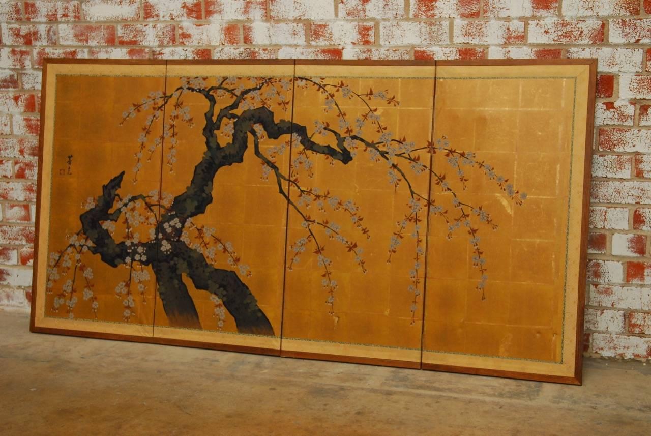 Dramatic Japanese four-panel Byobu screen featuring a large Sakura or cherry blossom tree on squares of gold leaf paper. The beautifully painted branches Stand out against the gilt background and are contrasted further by the delicate red and white