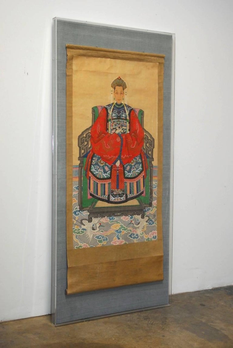 Monumental Chinese Qing ancestor scroll portrait painting of a high ranking official or Imperial court matriarch. Features a intricately decorated Ming style red robed matriarch depicted seated on a chair atop a brightly colored carpet. The rug has