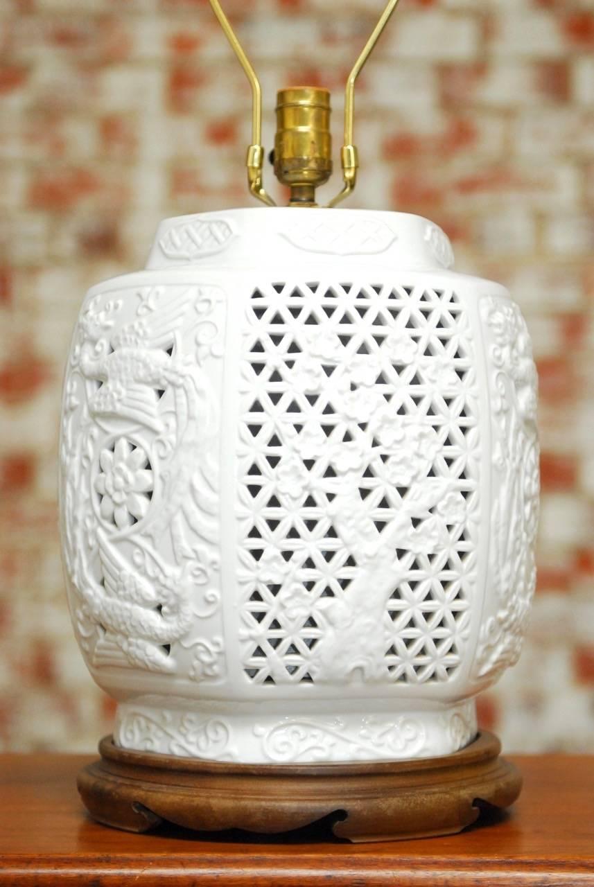 Mid-Century Modern Chinese blanc de chine porcelain vase table lamp. Features a pierced body decorated with birds and blossoms that lights up from the inside of the vase diffused with a paper lining. Topped with an Asian hat shaped bamboo shade and