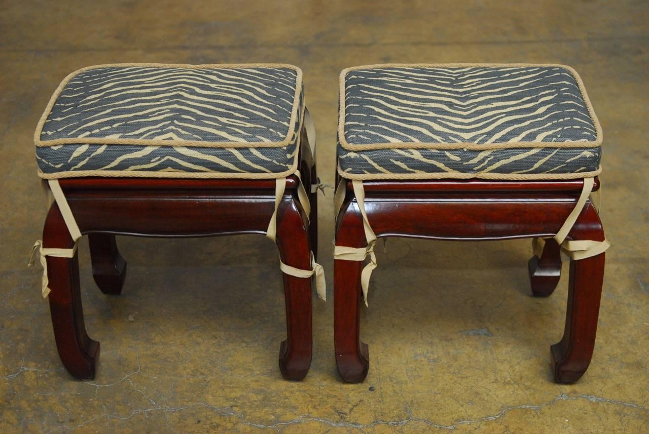 Exquisite pair of Chinese rosewood carved Ming style foot stools with zebra print upholstered cushions affixed with ballerina straps. Featuring a deep rich rosewood finish and a floating top panel. Supported by square legs with chow feet. Measured