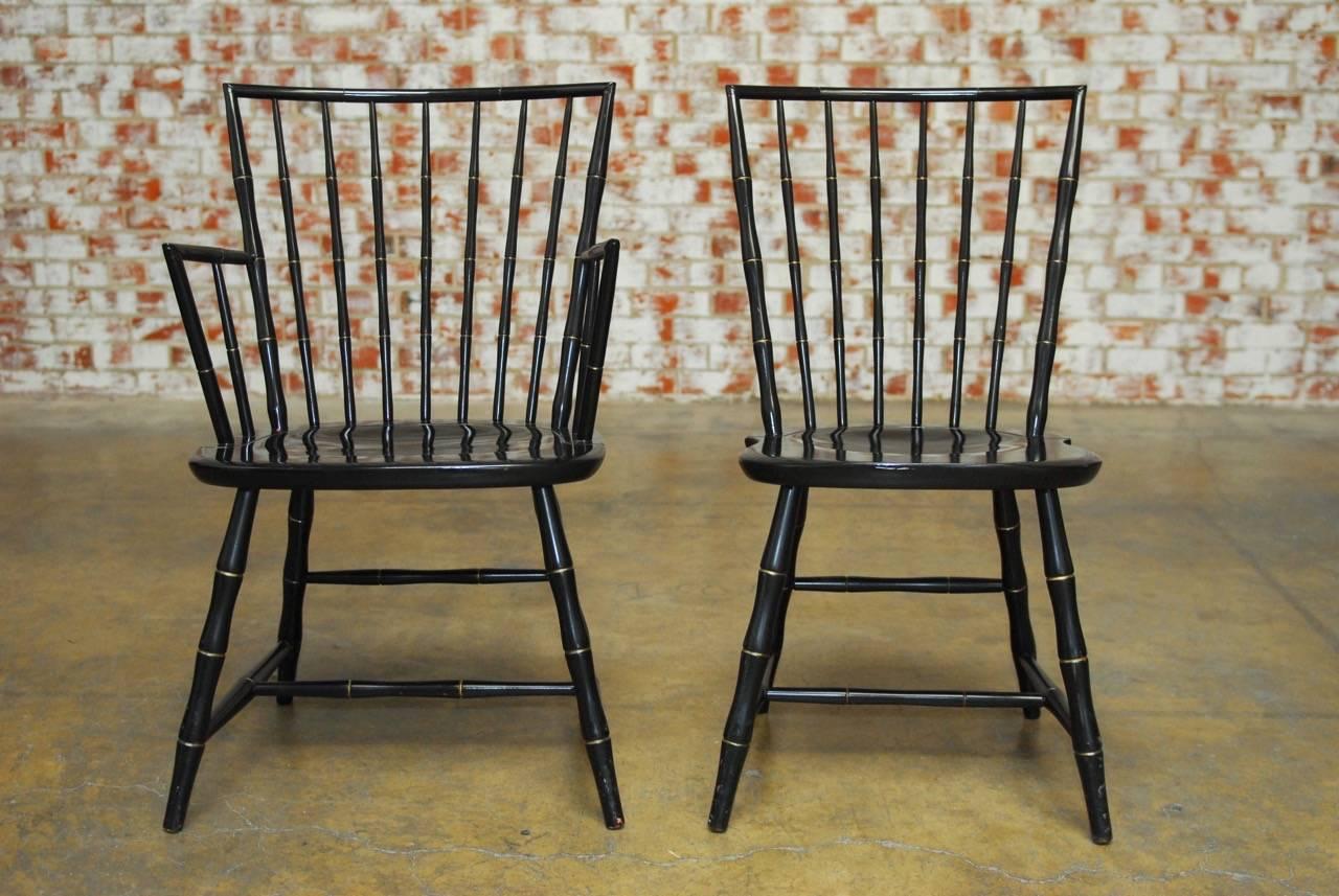 American pair of black lacquer and faux bamboo Windsor chairs produced by Nichols and Stone, America's oldest furniture company. Features a hand-carved faux bamboo hardwood frame finished with black lacquer and gilt accents. One armchair and one
