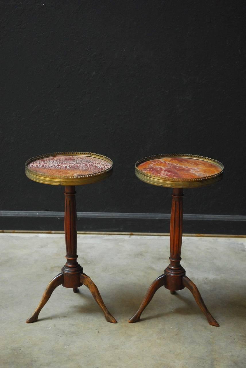 Outstanding pair of French Louis XVI style gueridon drink tables featuring round marble galleried tops. Fascinating veined marble with red, orange and white set in etched brass borders. Supported by a turned and fluted column. Ending in a tripod