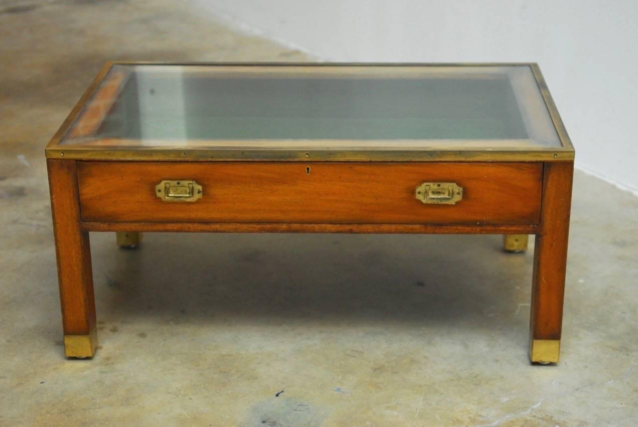 Distinctive 19th century English solid mahogany coffee table featuring a glass display case made in the Campaign style. Brass-mounted case with a large opening drawer for displaying memorabilia lined in green felt. Each side of the table has large