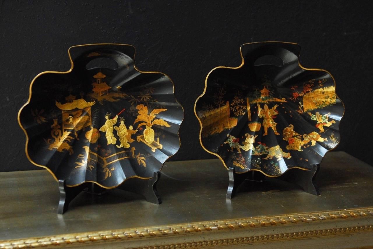 Gorgeous pair of English papier mâché crumb trays featuring a japanned finish. Made in the English Chinoiserie Revival taste of the late 19th century. Fashioned in the shape of shells and decorated in gilt. Included are two ebonized display stands.