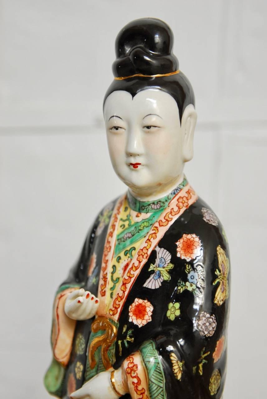 Verigated Chinese Famille Rose style enameled porcelain statue of a beauty. Featuring predominant colors of the classic famille palette. Famille juane (yellow), famille noir (black), famille rose (red), and famille verte (green) all represented on