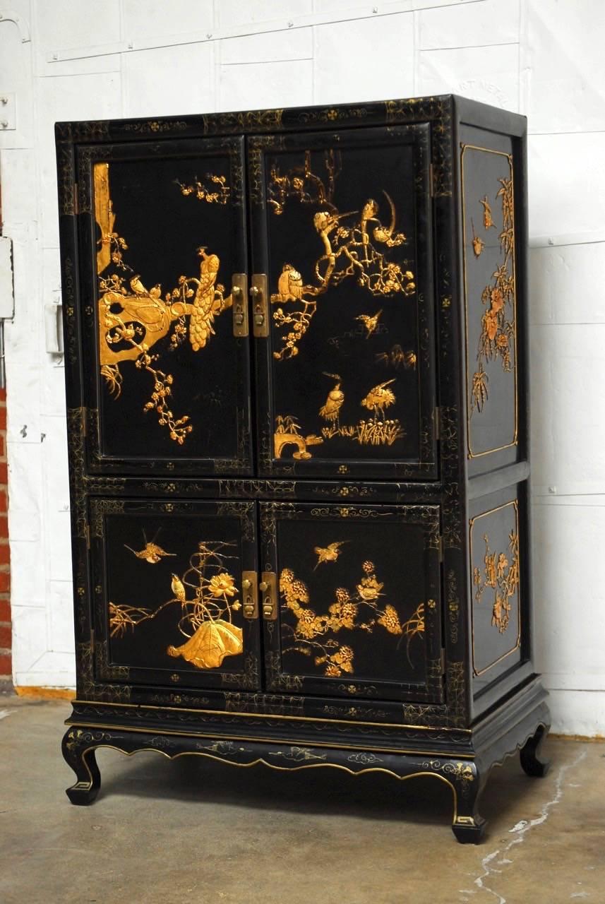Extraordinary Chinese gilt lacquered cabinet on stand. Features a Jappaned case embellished with relief carved flora and fauna in gilt applied to three sides. Amazing example of fine Chinese export decorated with gilt painted accents on the inside