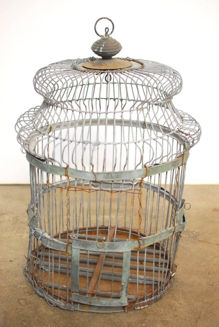Rare 19th century French hanging birdcage made of zinc. Features a domed top and a rich, distressed shabby finish. Sliding door works and still retains the French makers plaque. Beautiful patinated finish on the zinc with reinforcements. 