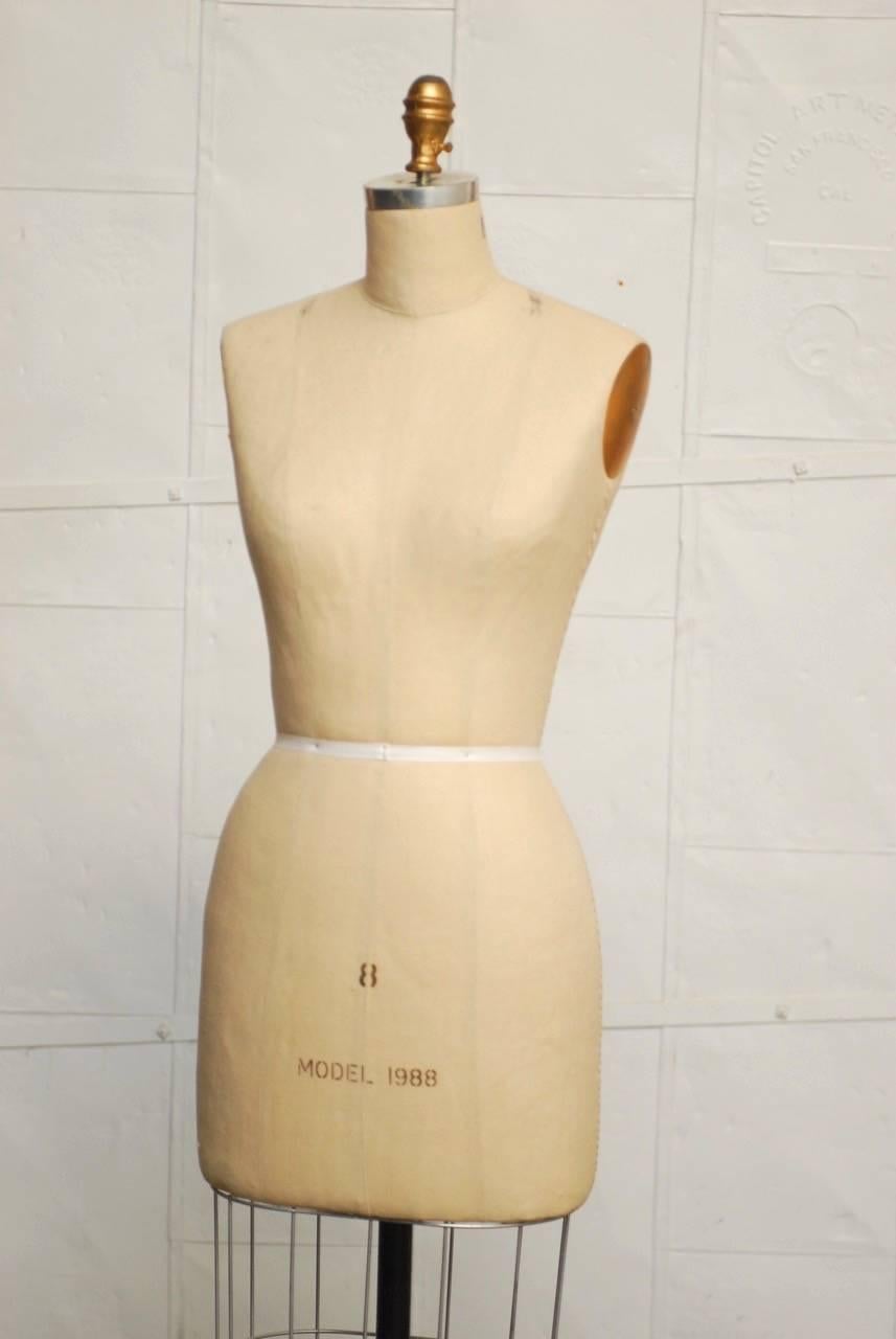 Vintage ladies model dress form mannequin featuring a canvas body labeled size 8. Mounted to a cast iron stand finished in black. Rolls on metal casters in excellent condition.