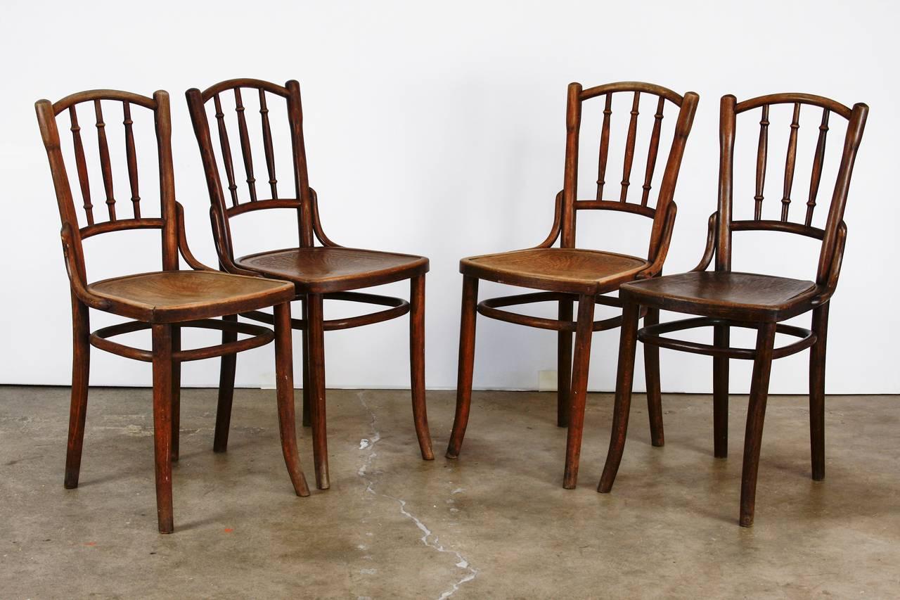Fabulous set of four Thonet bentwood dining chairs model A9800 constructed from beech. Rare style featuring a spindle back and a stamped seat with an Art Nouveau style palmette decoration. Uniquely styled chair has a rounded crest back and legs