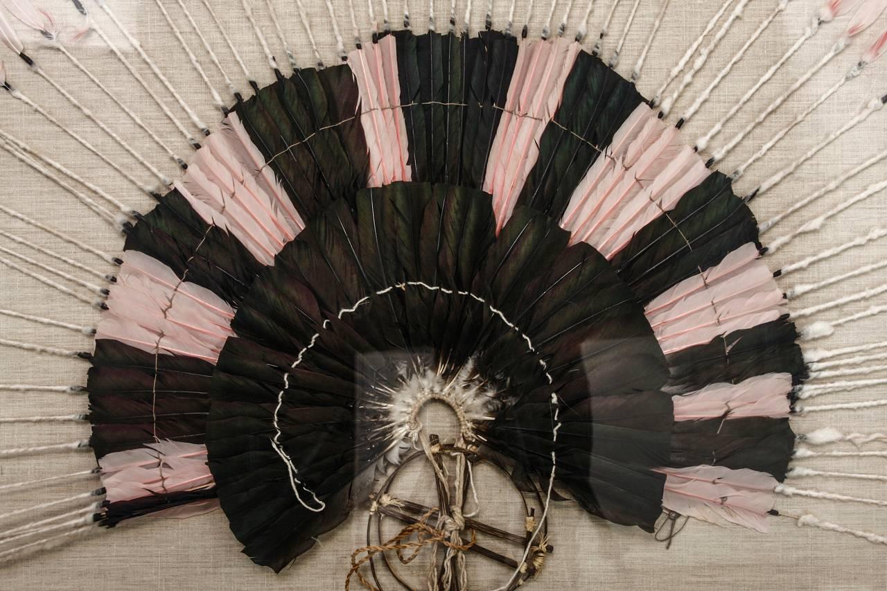 Fantastic native American feather headdress featuring pink and black plumage displayed in a Lucite box. This beautiful piece is fanned out and mounted on a natural linen covered board. The headdress is centered by two round dream catcher style