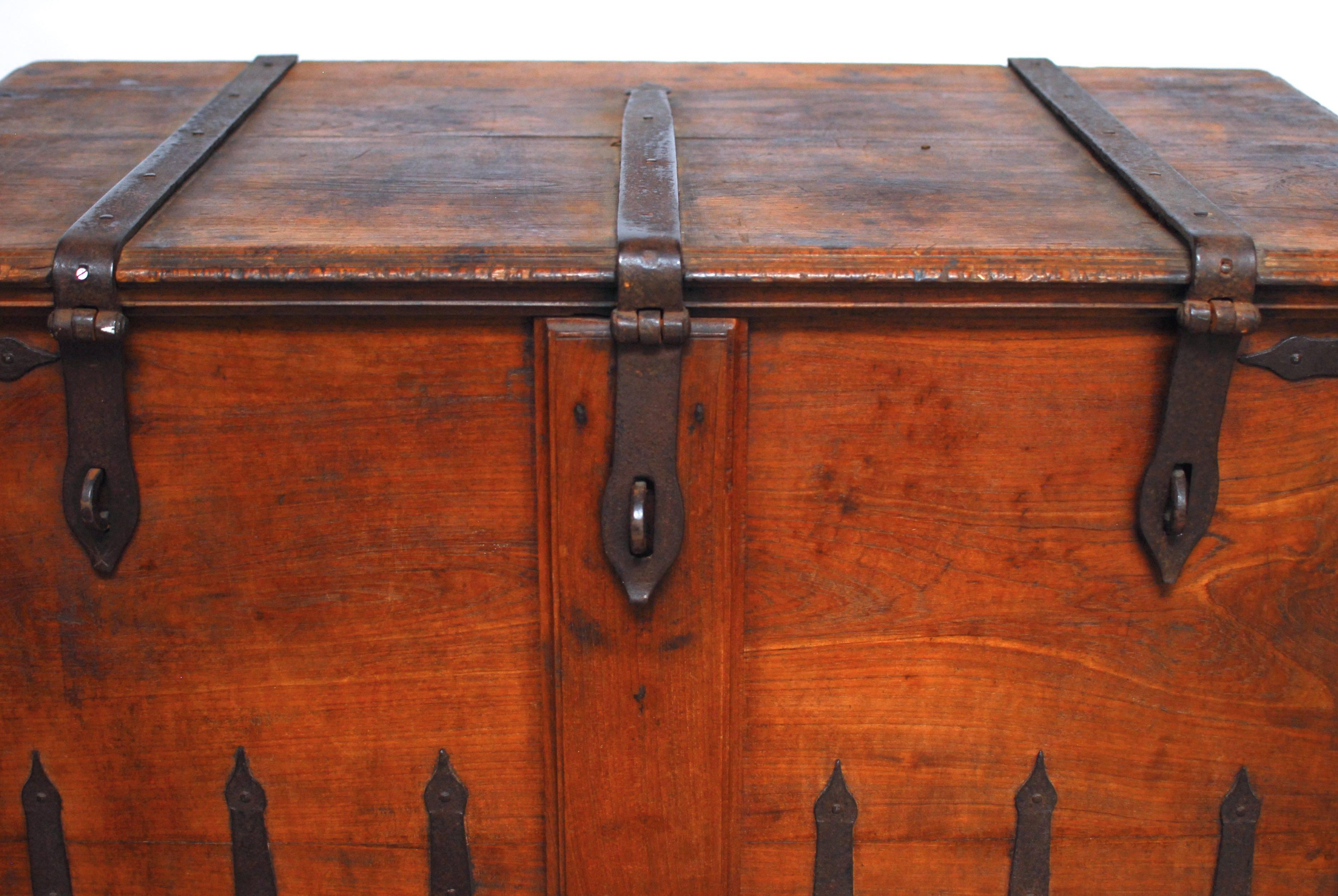 Rustic 18th century Indian Damchiya dowry hope chest sitting on Primitive wheels and featuring iron strapping and lock plates. Lovely rich patina on the hand-carved teak. Decorated on all sides and top with thick, heavy iron straps that have an Arab