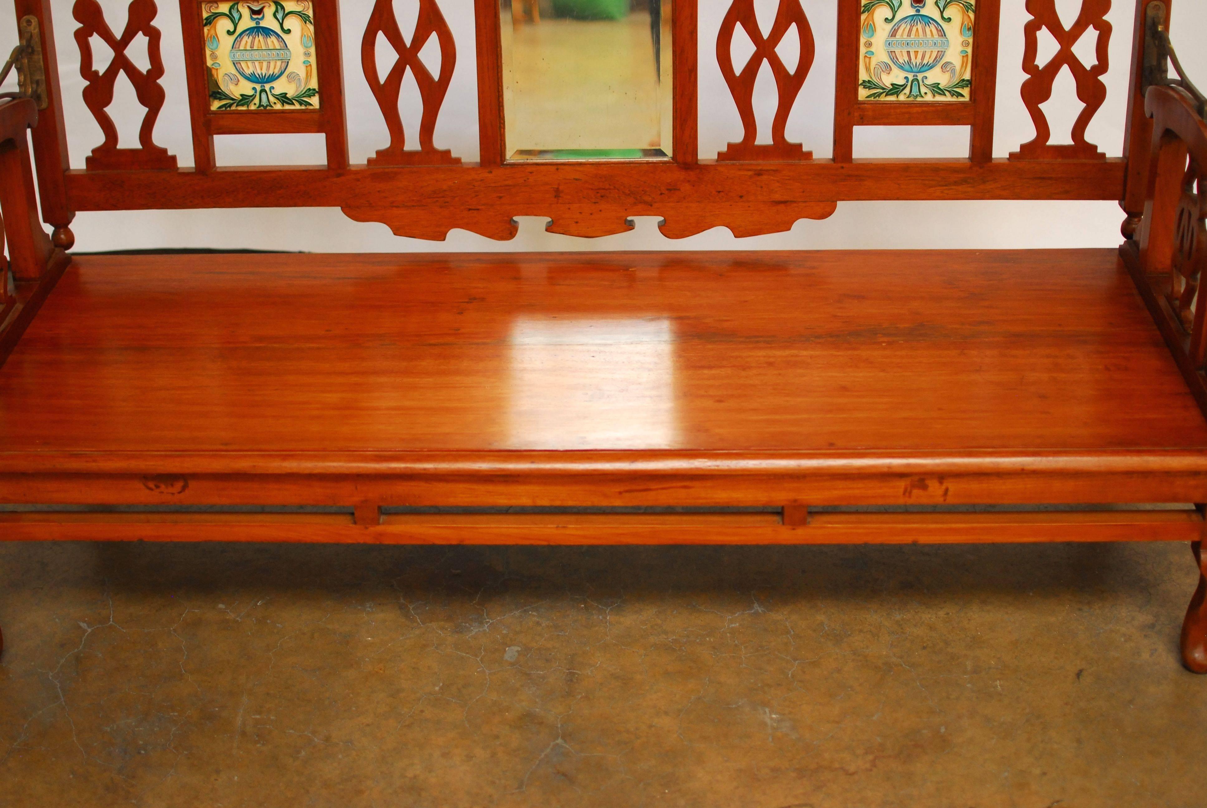 Impressive British Colonial swing back bench made entirely of hand-carved teakwood featuring a rotating back to expose sunrise or sunset orientation. The bench has its original hooks on all four corners for hanging. The backrest features Hindu style