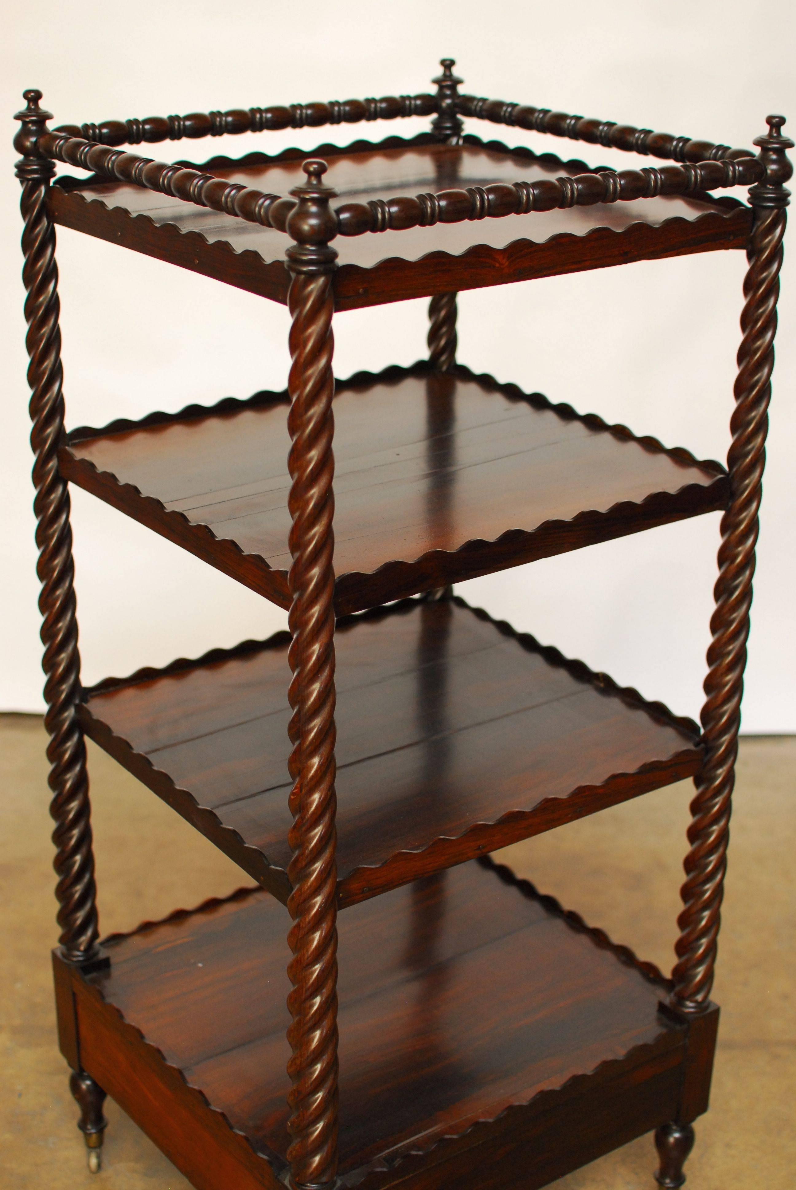 A gorgeous 19th century English Regency mahogany etagere with four galleried shelves. Featuring barley twist turned supports and the top tier having a turned wood gallery. The shelf rests on original brass casters and turned finials surmount the top