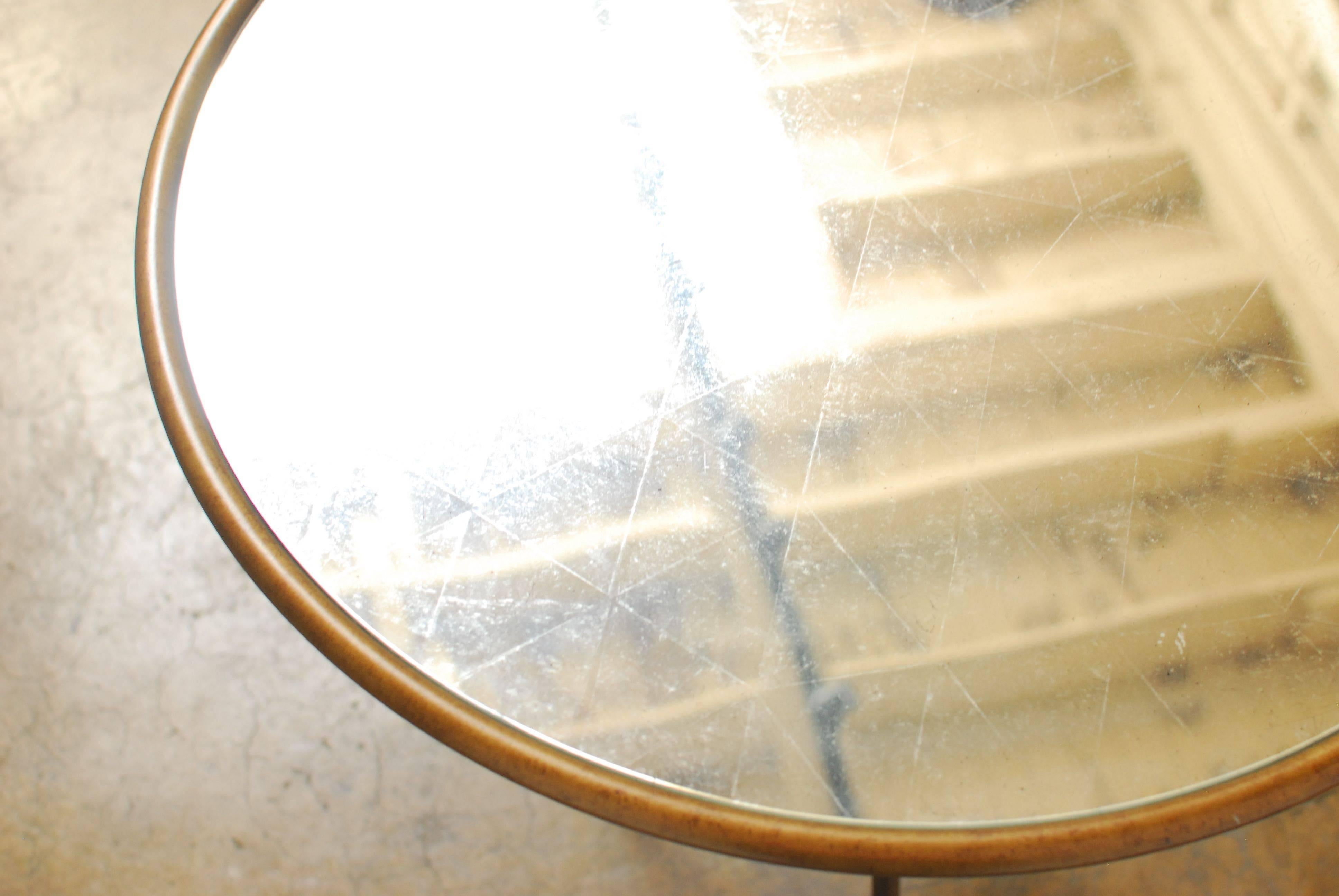 Round gilded iron occasional side table made in the manner of Rene´ Drouet with an iron rope knot base and finished in a gilt metal. The top features an antiqued round mirror top inlay with a geometric pattern etched into the glass. The mirror has a