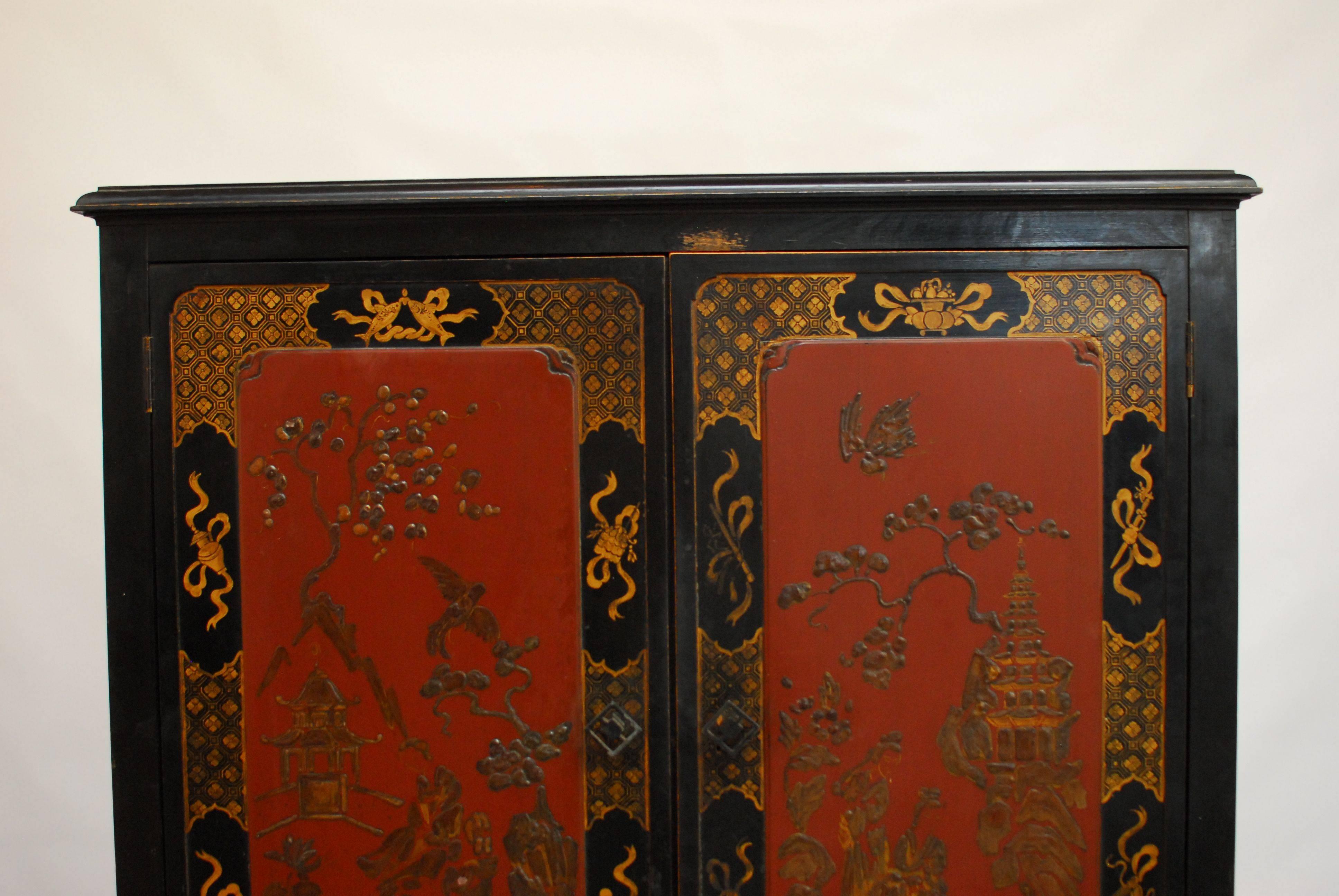 Chinoiserie black lacquer cocktail or bar cabinet fronted by double doors and one drawer below. The front decorated with pagodas and birds on a gilt fretwork case. Sits atop a raised stand with square legs and humpback stretchers. Greek key