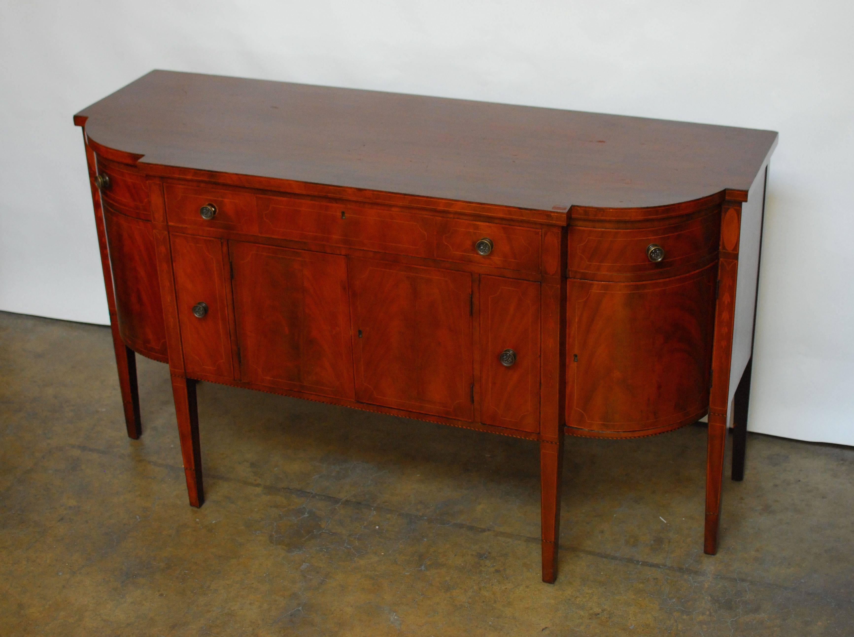 Exceptional 19th century bow front mahogany sideboard finely constructed with flowing grains of mahogany veneers throughout the front. Fully developed sideboard with bottle drawers and flanked by convex side drawers. Embellished with line inlay on