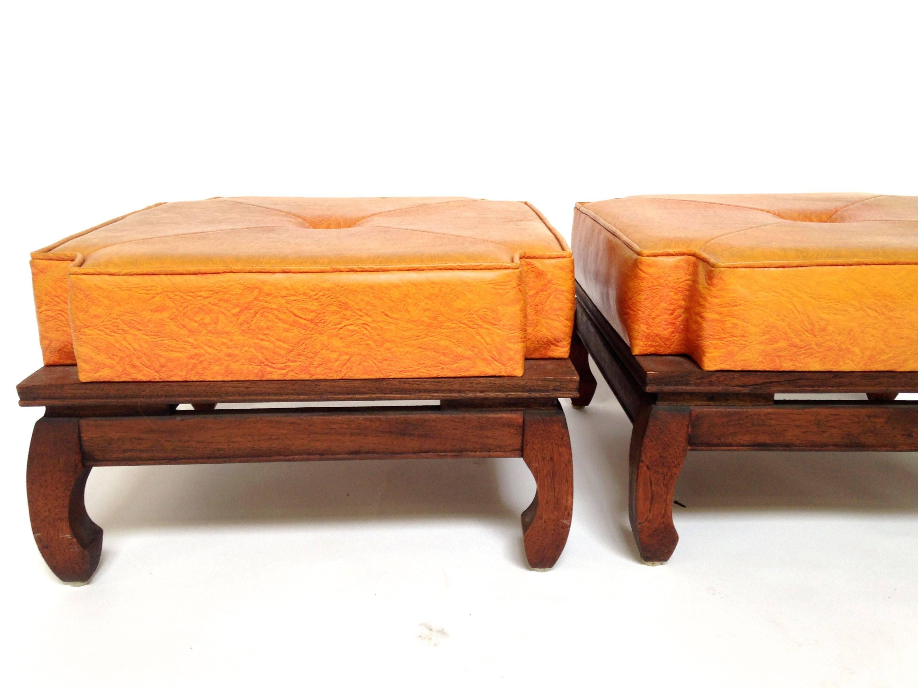 A pair of 1960s, Mid-Century Modern Chinese foot stools by famous designer Ricardo Lynn with a carved base and featuring traditional chow legs and a floating top panel. Orange tufted cushion with lots of padding that sits tall. These have a great