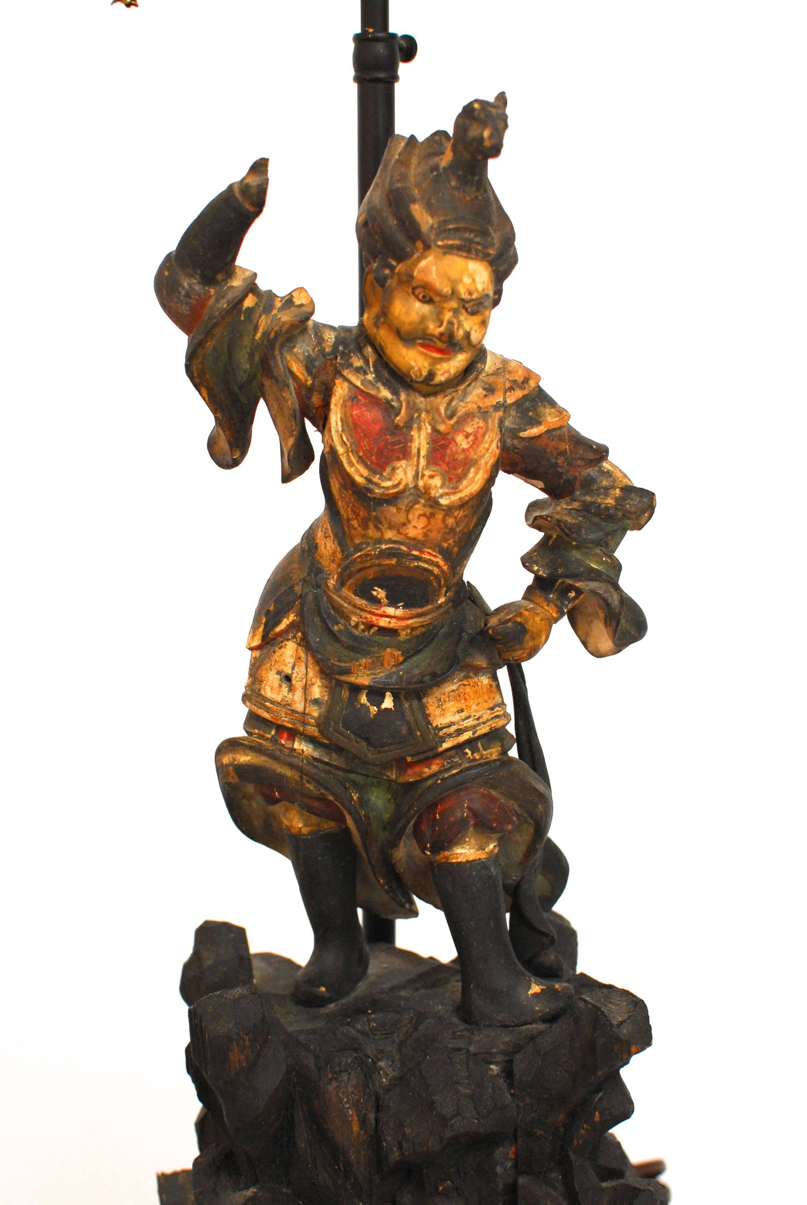 Antique polychrome carved Chinese warrior figurine table lamp. Intricately detailed warrior with a colored costume featuring reds, greens, blacks and whites. Solid wood base with a gilt finish and brass trim.  Circa 1880s with minor chips and fading