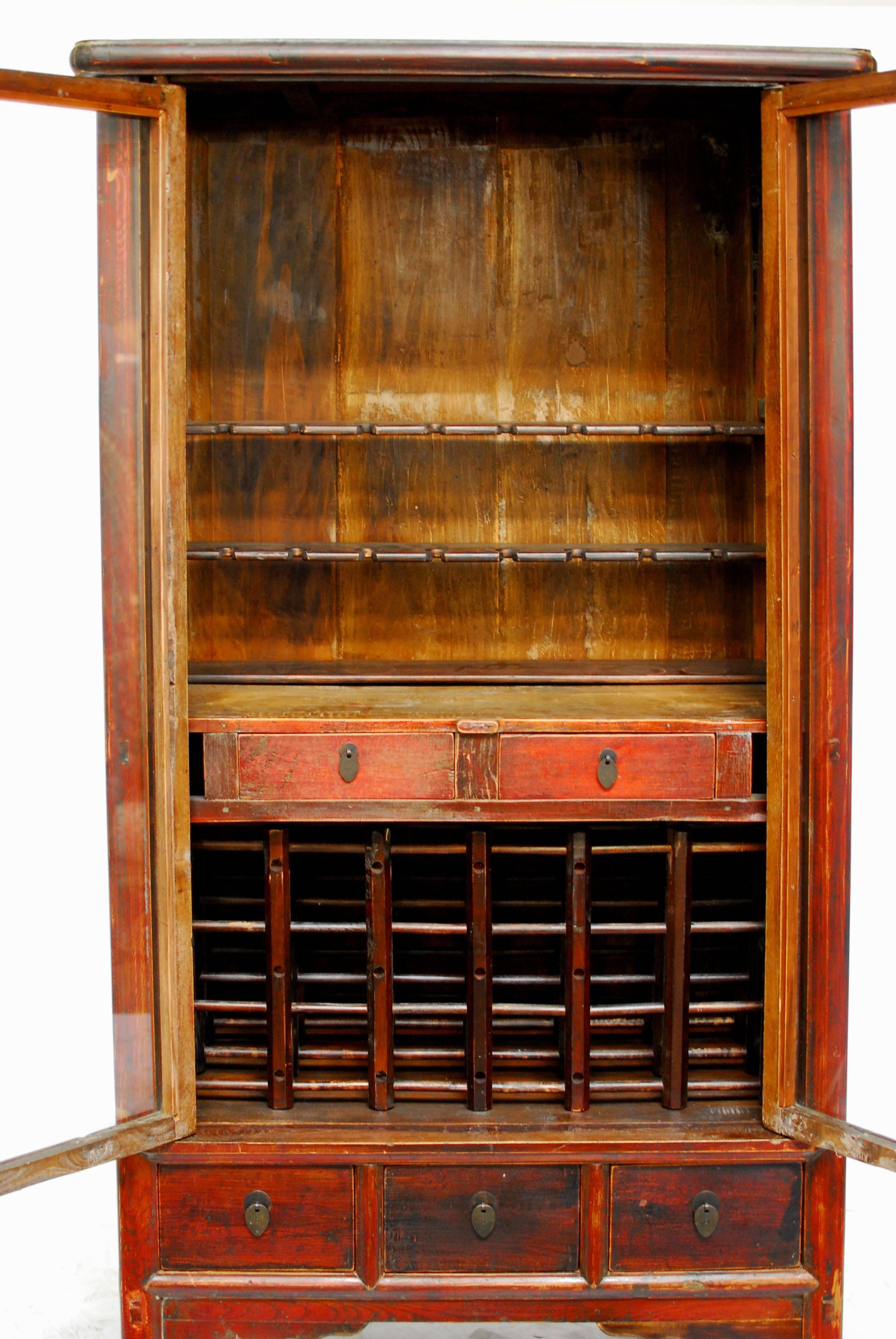 Antique Ming style red lacquer tapered wine cabinet converted by Terra Nova of Beverly Hills, CA. This tapered chest estimated, circa 1800s features glass front doors and three lower drawers on the bottom. The inside has been repurposed with