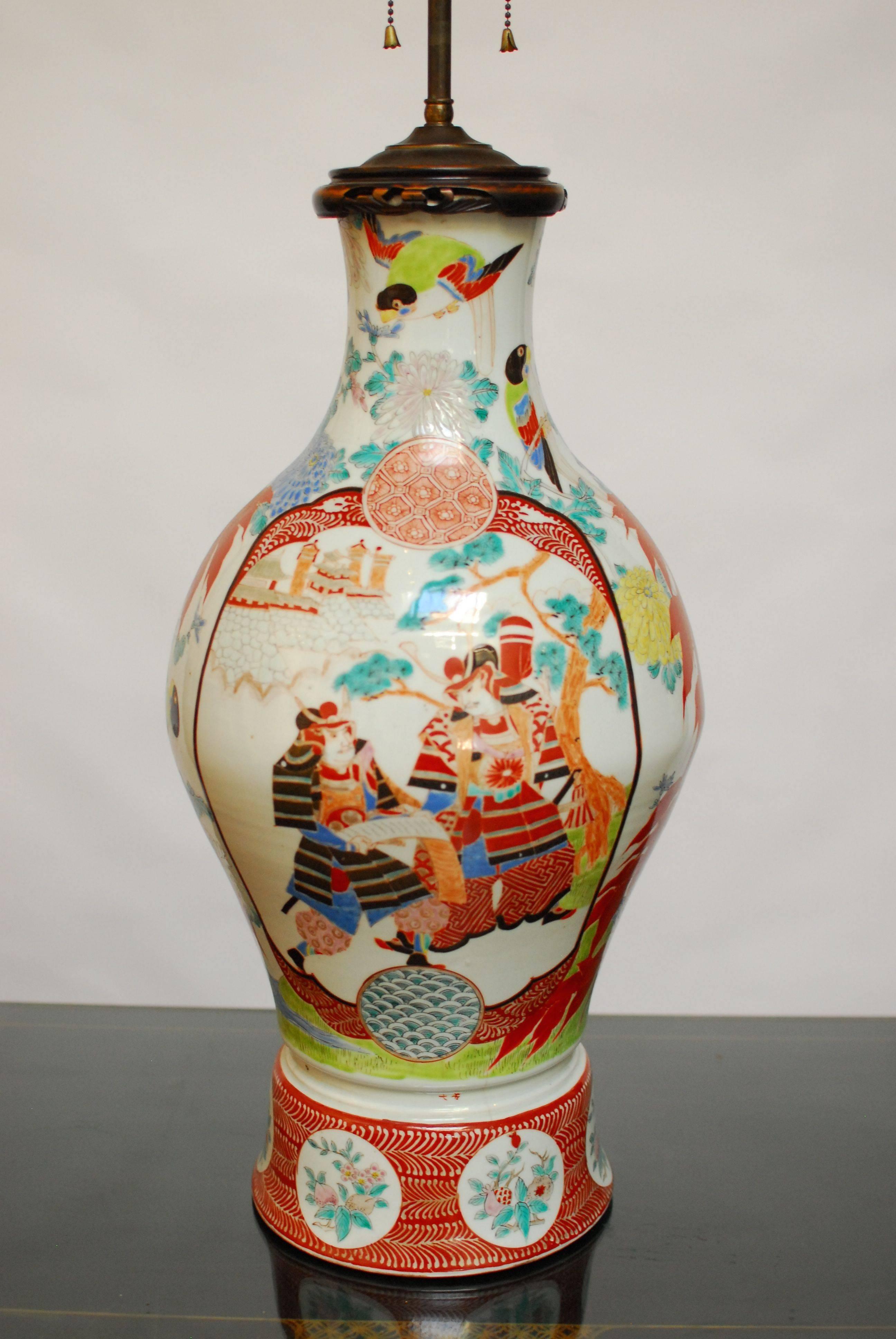 Antique Chinese porcelain urn mounted as a table lamp. Polychrome decorated with Japanese scenes of warriors on each side. Dramatic and vibrant colors with a carved lid and brass hardware. Double light head with an adjustable telescoping top.